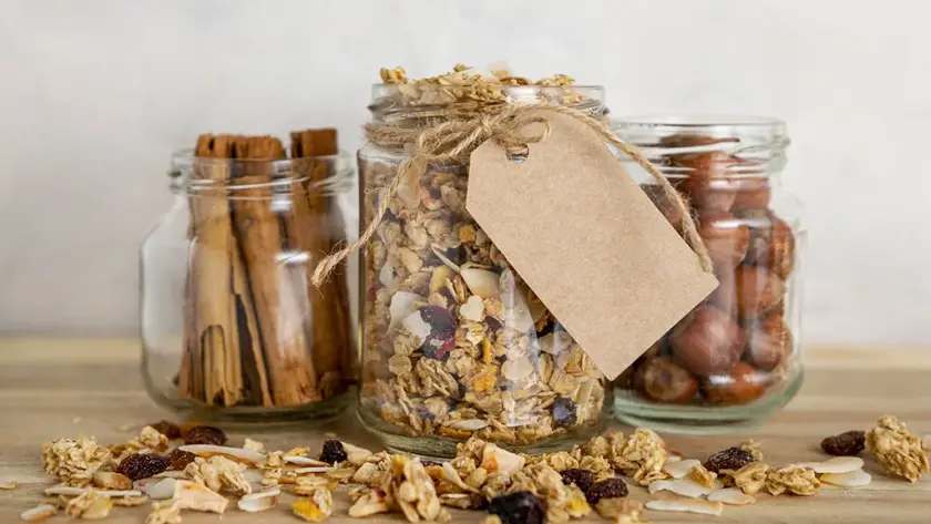 Frascos de vidrio con granola, canela y frutos secos con etiqueta para etiquetado de alimentos.